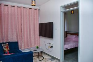a bedroom with a bed and a tv and a blue chair at TSAVO Room 202 in Kiambu