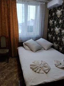 Un dormitorio con una cama con sábanas blancas y una ventana. en Готель Колізей, en Khmelʼnytsʼkyy