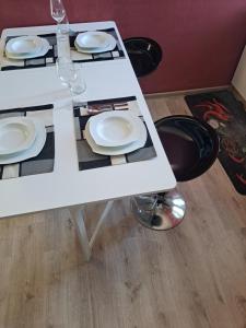 a white table with plates and wine glasses on it at Peron 4-City & Station Stay in Rijeka