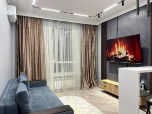 een woonkamer met een blauwe bank en een tv bij Everest Home in Alma-Ata