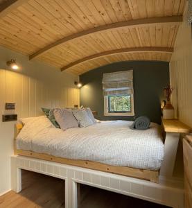 a bedroom with a large bed with a wooden ceiling at Cornwall Shepherds Hut - Hot Tub & Cosy Log Burner in Saint Day