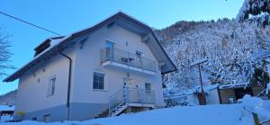 a white building with a balcony in the snow at Ruheoase Sternig in Bad Bleiberg