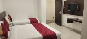 a hotel room with two beds and a television at Hotel Orion Inn in Tirupati