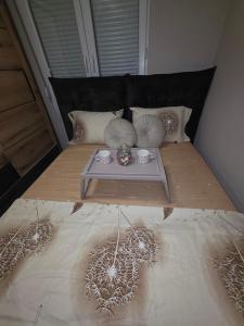 ein Bett mit einem Tisch und Kissen darauf in der Unterkunft Apartman Warm nest in Kraljevo + 8 Fotos