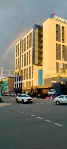 un arc-en-ciel sur un immeuble avec des voitures garées dans un parking dans l'établissement Рахмет, à Petropavlovsk-Kamtchatski