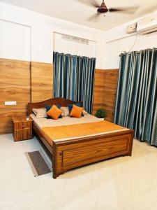 Un dormitorio con una gran cama de madera con almohadas naranjas. en Harichandhanam Inn - Entire Flat, Ground Floor, 200m From East Nada Guruvayur, en Guruvāyūr