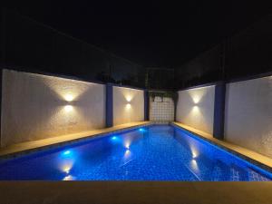 - une piscine avec des lumières bleues dans un bâtiment dans l'établissement Zomak Villa 3BHK in Lonavala with pvt pool By Bungalows In Lonavala, à Lonavala