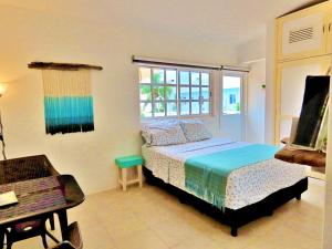 a bedroom with a bed and a desk and a window at Casa Brisamar , Studios in Puerto Morelos