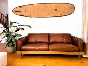 een bruine leren bank met een surfplank aan de muur bij Porto Surf Lodge in Porto