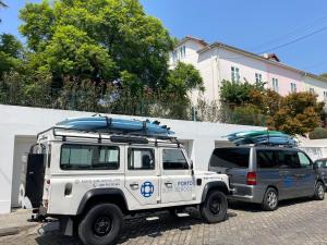 een witte jeep en een busje met surfplanken erop bij Porto Surf Lodge in Porto