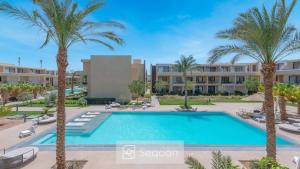 an image of a swimming pool in a resort with palm trees at Serenity Studio in G-Cribs in El Gouna