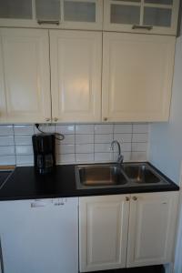 une cuisine avec un évier en acier inoxydable et des armoires blanches dans l'établissement Vannebodagatan, à Frövi