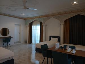 Una habitación de hotel con una cama, un escritorio y una mesa. en De Sultana Villa, en Mascate