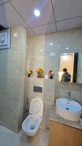 Un baño con inodoro y lavabo y un hombre tomando una foto. en Comfystays, en Greater Noida