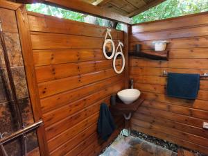 a bathroom with a wooden wall with a sink and mirrors at Kaz Coco Bungalow in Bouillante