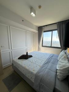 une chambre avec un grand lit avec une grande fenêtre dans l'établissement unixx seaview, à Pattaya (sud)