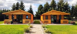 Nowe CzapleにあるMużakowski Zakątekの草と木々のある公園にある2つの木造の小屋