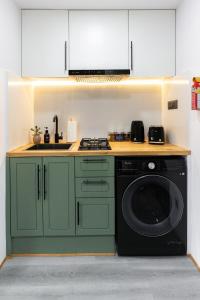 cocina con armarios verdes y lavadora en Cosy 1 Bedroom Studio with King Bed Kitchenet in Central Kathmandu with Terrace, en Katmandú