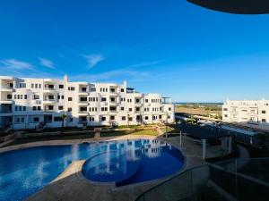 a large swimming pool in front of a building at Colina Smir par Immo Marina Vacances de Rêve C1-10 in Oulad Akkou