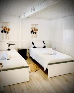 - 2 lits dans une chambre dotée de murs blancs et de parquet dans l'établissement IRIS Boutique Rooms, à Corinthe