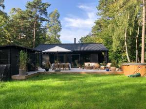 a black house with a patio and a yard at Elegant New Cottage On Quiet Woodland Site in Nykøbing Sjælland