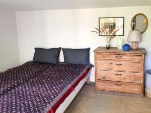a bedroom with a bed and a dresser with a mirror at Elegant New Cottage On Quiet Woodland Site in Nykøbing Sjælland