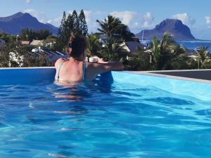 a woman sitting in a swimming pool looking out at the ocean at Sunset Corner in Rivière Noire +3 photos