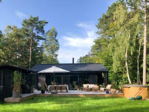 a black house with a patio in a yard at Elegant New Cottage On Quiet Woodland Site in Nykøbing Sjælland +25 photos