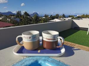 two coffee mugs sitting on a tray on a balcony at Sunset Corner in Rivière Noire
