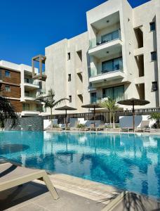 帕拉利米尼Fall In Paradise的一座带遮阳伞的建筑前的游泳池