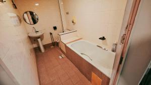 un baño con bañera y lavabo en Wangsa Village Inn, en Ulu Tiram