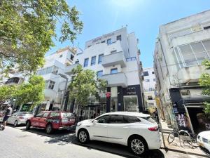 un coche blanco aparcado en una calle de la ciudad con edificios en 2Bedroom Suite 7 with shelter, en Tel Aviv