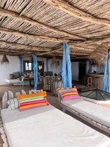 two beds in a room with blue curtains at Dar Gecko in Sidi Kaouki