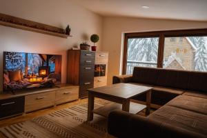 a living room with a couch and a tv and a table at Apartman Monti Vlašić in Vlasic