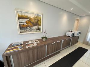 a reception desk in a room with a picture on the wall at Hotel Vitória - Guaíra in Guaíra