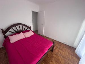 a bedroom with a red bed with two pink pillows at 2 Ambientes Gascon in Mar del Plata