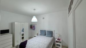 a white bedroom with a bed with blue pillows at Vidamar in Abades