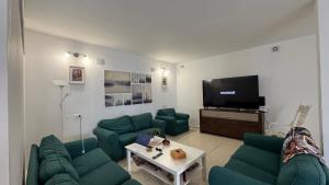 a living room with green couches and a flat screen tv at Vidamar in Abades