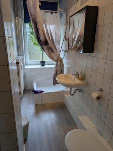 a bathroom with a sink and a toilet and a window at Stadtnah an der Förde 75 in Flensburg