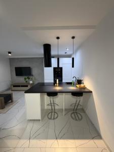 une cuisine avec un îlot et deux tabourets de bar dans l'établissement Apartament 8, à Łobez