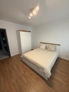 une chambre avec un lit blanc et un parquet dans l'établissement Apartament 8, à Łobez