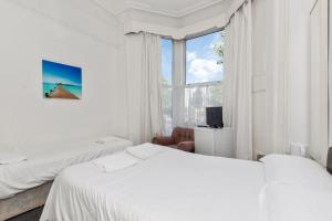 une chambre blanche avec deux lits et une fenêtre dans l'établissement Amhurst Hotel, à Londres