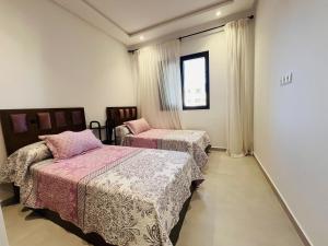 a bedroom with two beds and a window at Colina Smir par Immo Marina Vacances de Rêve B1-10 in Oulad Akkou +5 photos