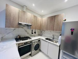 a kitchen with wooden cabinets and a dishwasher at Colina Smir par Immo Marina Vacances de Rêve B1-10 in Oulad Akkou