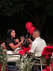 Ein Mann und eine Frau sitzen an einem Tisch mit roten Luftballons. in der Unterkunft Eco-Glamping Shalom in Mariquita + 206 Fotos