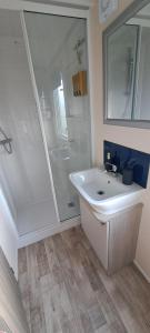 a bathroom with a white sink and a shower at Blue Lagoon Holiday ,Bude 79 in Cubert +32 photos