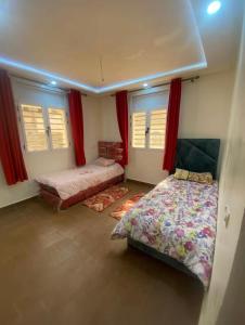 a bedroom with two beds and red curtains at Immeuble Elmo plage Mirleft in Mirleft