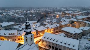 une ville enneigée la nuit, avec une tour d'horloge dans l'établissement Apartmani Mesko, à Gospić