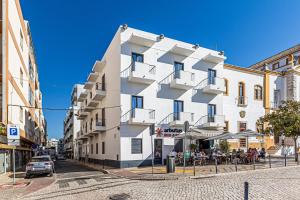 a white building on a street with people sitting outside at Arbutus Bed and Bar in Portimão