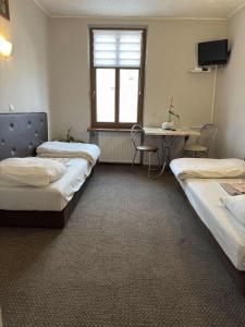 une chambre avec deux lits, une table et une fenêtre dans l'établissement Hotel Gryf, à Gryfice